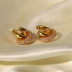 Close-up of interlocking hoop gold earrings showing pavé crystal details