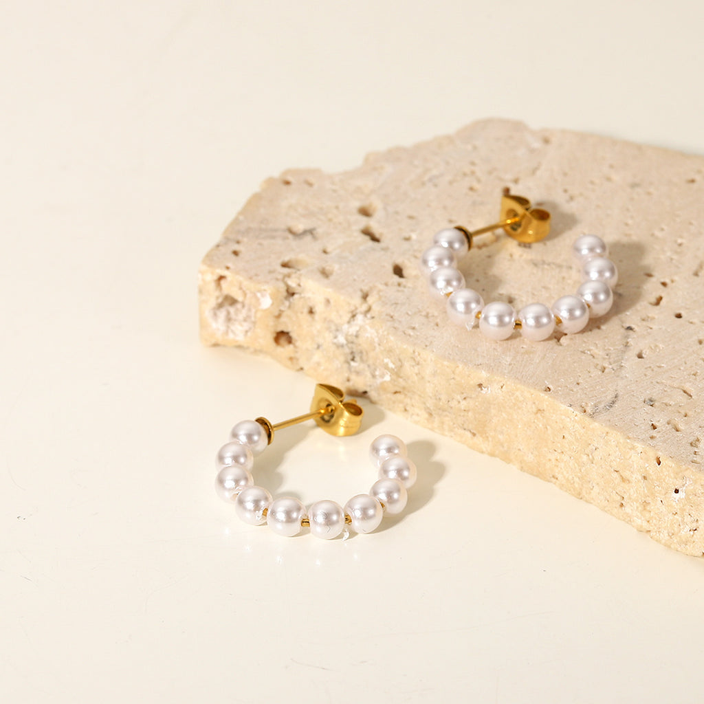 Close-up of gold C-hoop earrings with delicate pearls