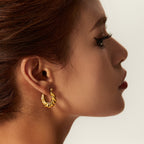 Close-up gold twisted hoop earrings, hinge clasp detail, fashion accessory