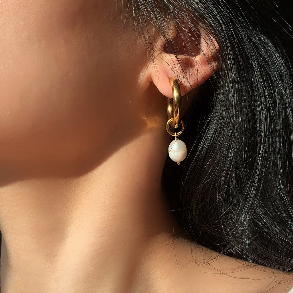 Close-up of gold hoop earring with organic pearl detail