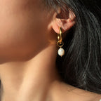 Close-up of gold hoop earring with organic pearl detail